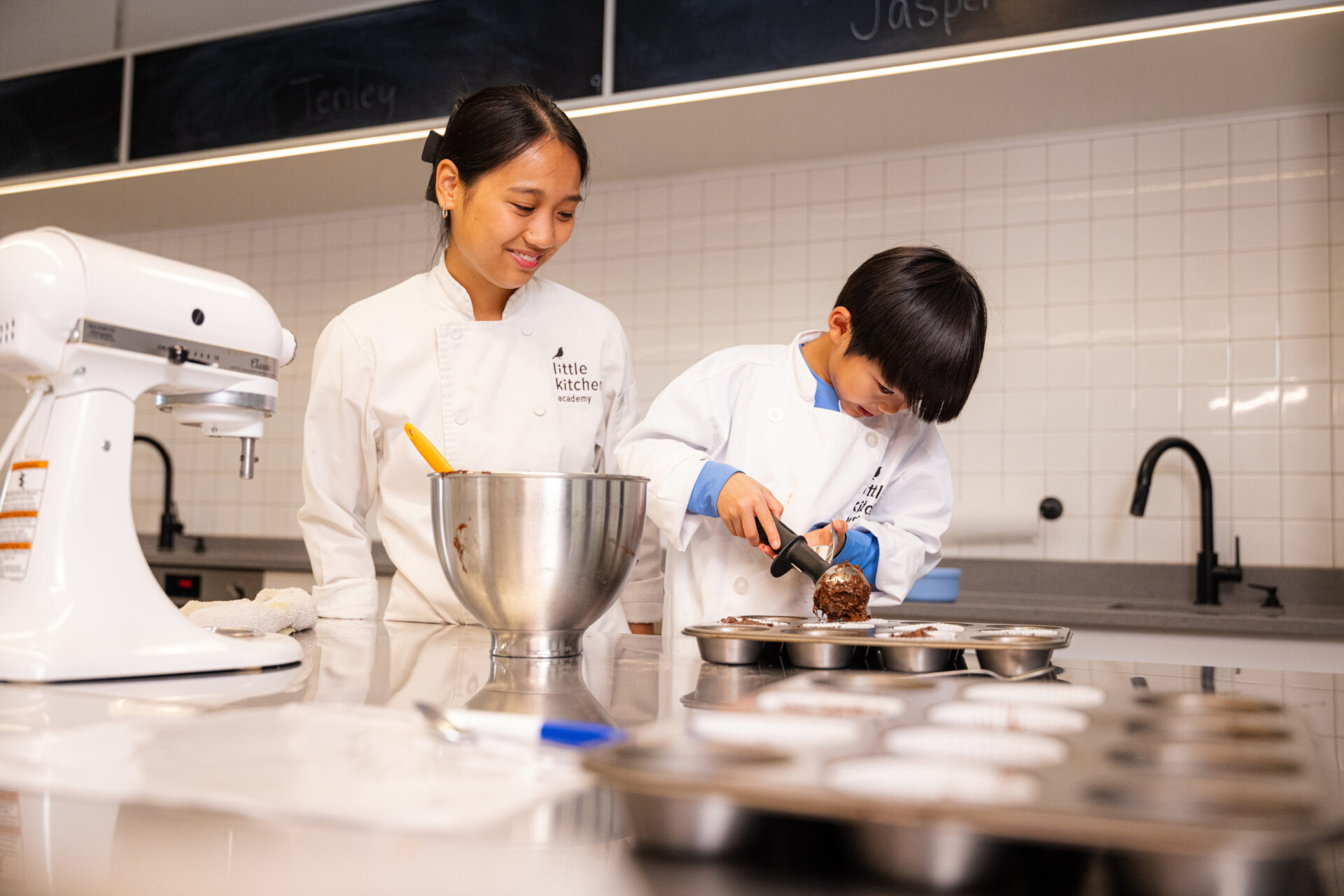 LKA student pouring batter into muffin tin beside instructor